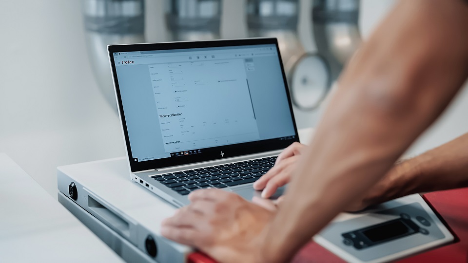 Operator using Trotec Ruby software on laptop to control laser engraving machine