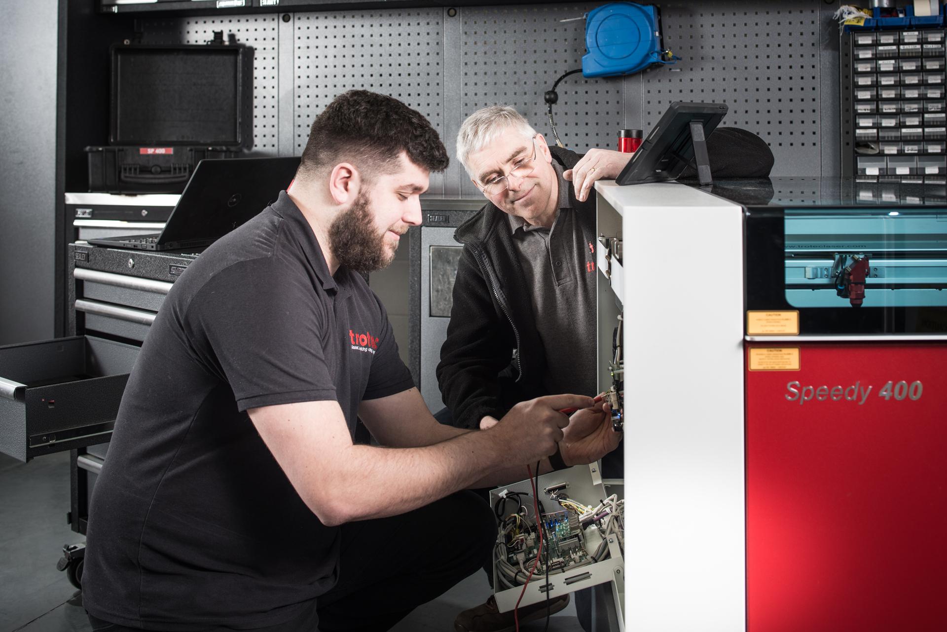 Technicians servicing Trotec Speedy 400 laser engraver in workshop