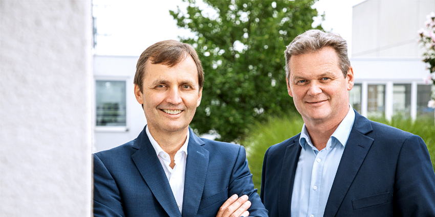 Trotec-Führungskräfte in Business-Anzügen stehen vor dem Firmensitz