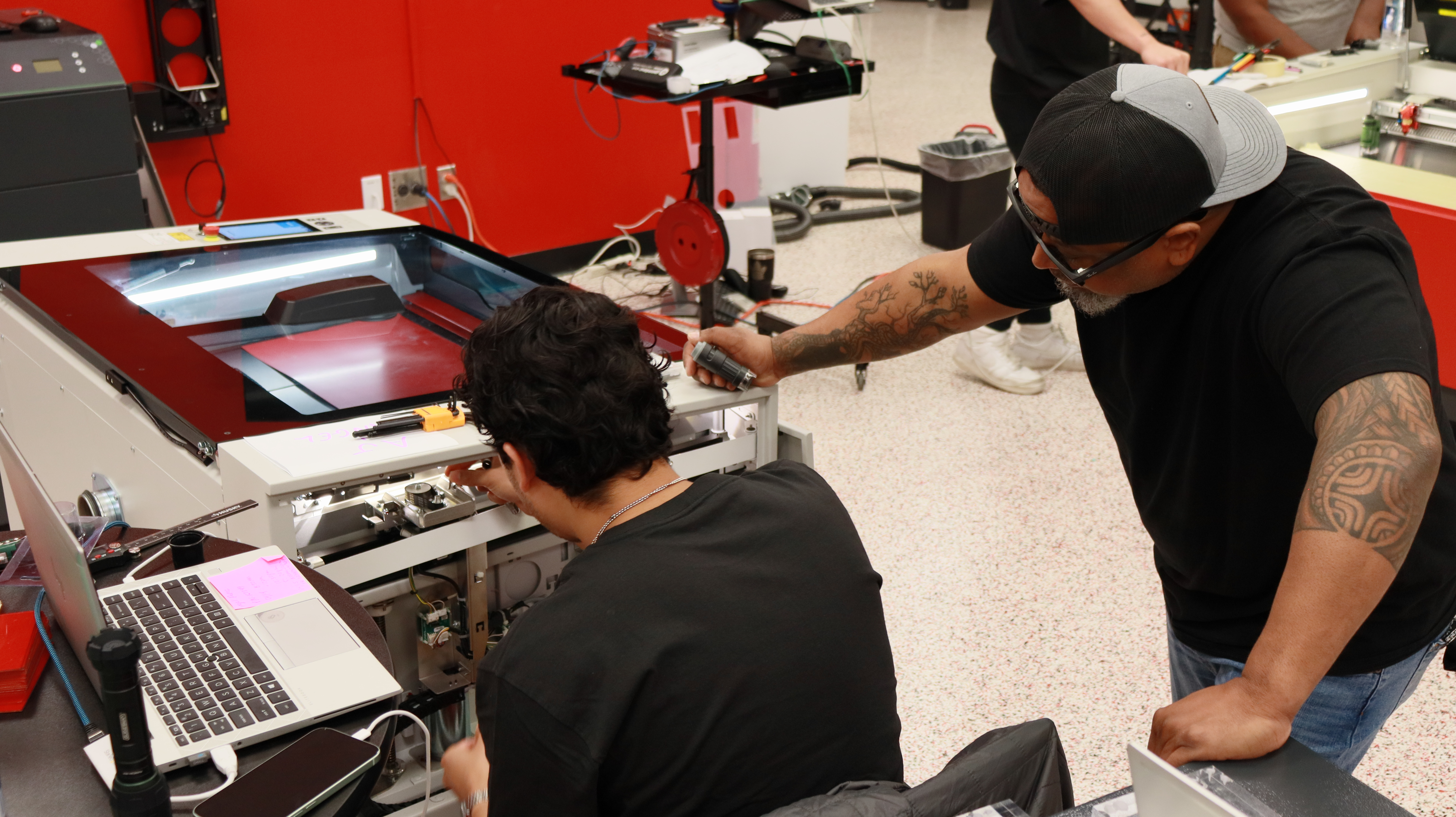 Technicians servicing Trotec Speedy series CO₂ laser cutter during maintenance session