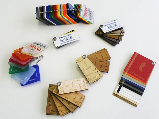 Muestras de materiales de grabado láser de Trotec, incluyendo TroLase, TroGlass, madera y muestras de LaserPaper