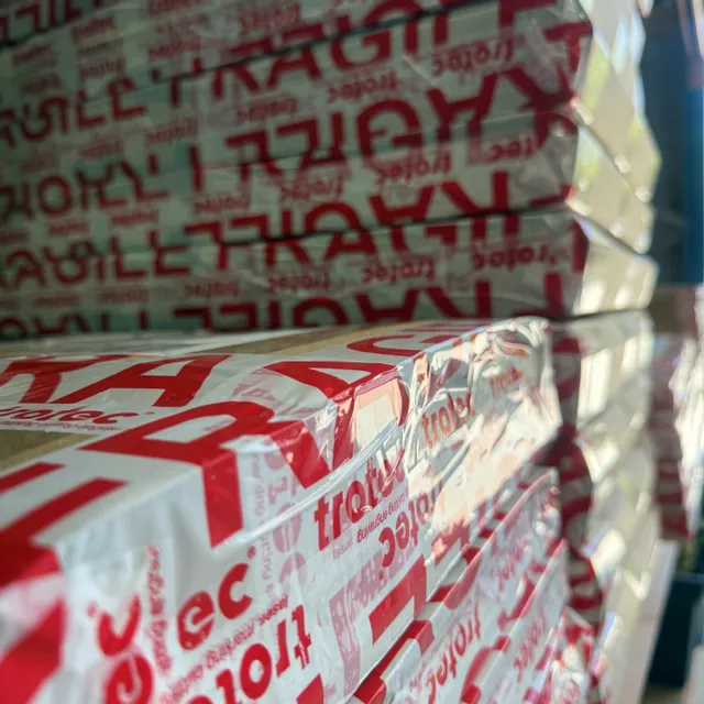 Stacked boxes wrapped in Trotec-branded fragile packaging, ready for laser engraving machine shipment