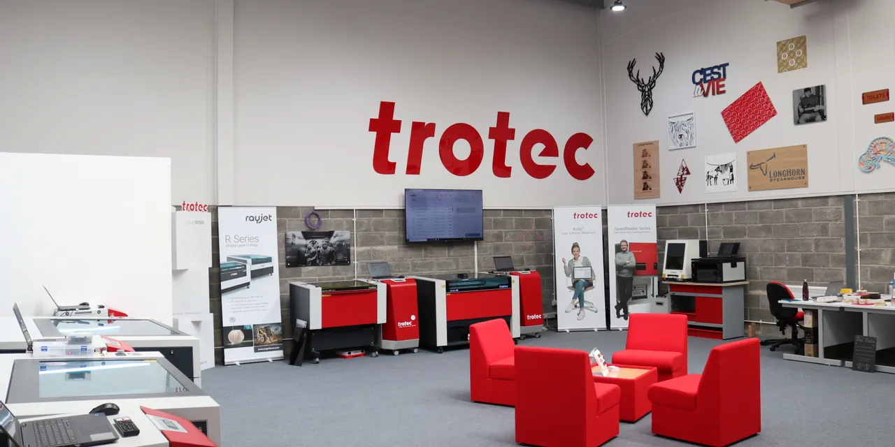 Trotec showroom displaying Speedy series laser cutters, R Series machines, and Ruby software banners