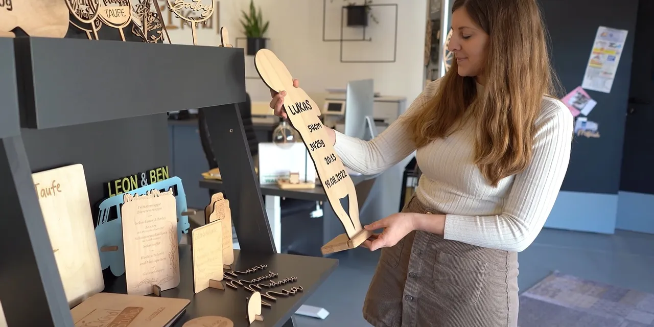 Woman displaying wooden signs created with Trotec CO₂ laser engraving machine