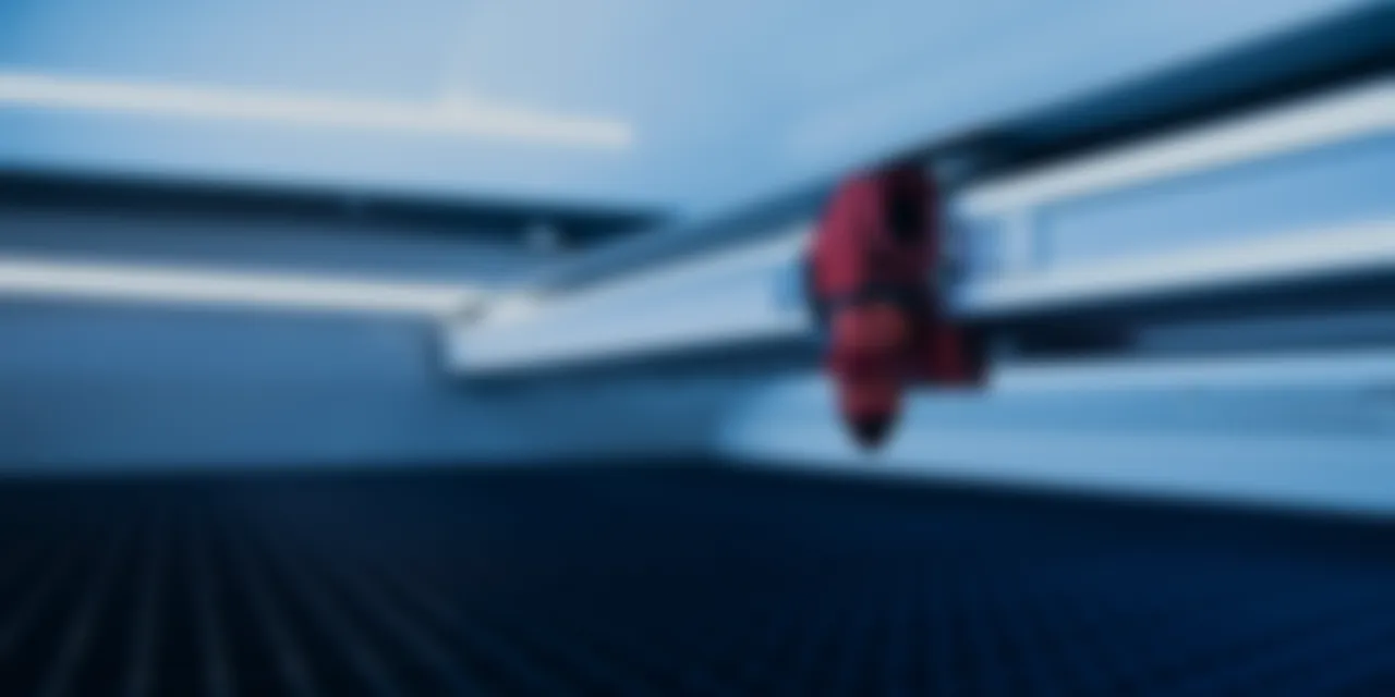 Close-up view inside Trotec Speedy series CO₂ laser cutter with engraving head and honeycomb cutting table