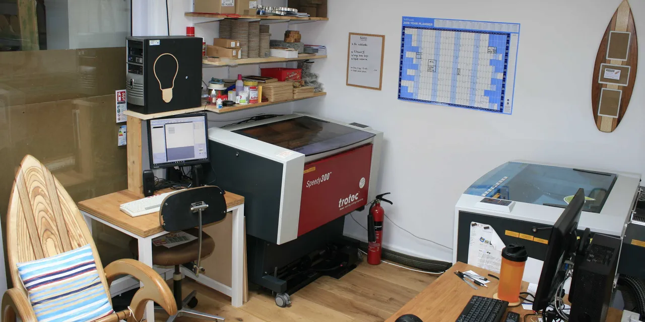 Trotec Speedy 300 CO₂ Laserschneider im Arbeitsbereich mit Computer und gravierten Holzproben