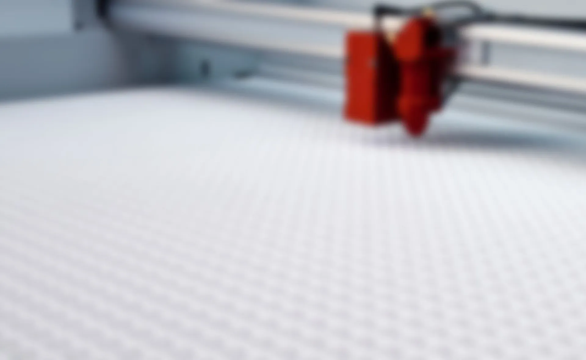 Testa del laser cutter Trotec sopra il tavolo con griglia a nido d’ape nella macchina per incisione CO₂