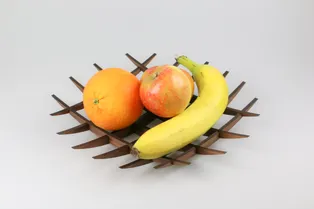 Laser-cut wooden fruit bowl made with Trotec CO₂ laser holding banana, apple, and orange