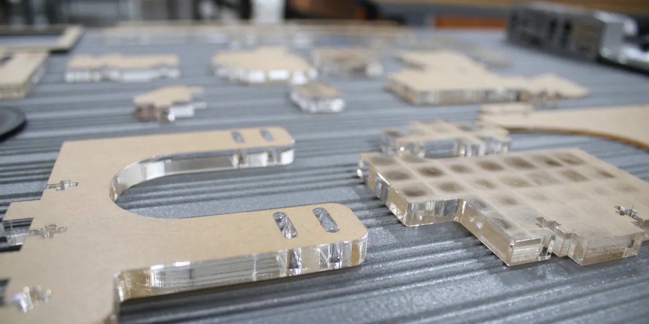 Lasergeschnittene Acrylteile auf dem CO₂-Laserschneiderbett der Trotec Speedy-Serie