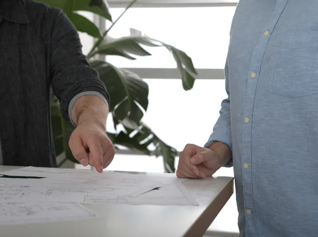 To personer gennemgår tekniske tegninger til et projekt med laserskærer eller graveringsmaskine