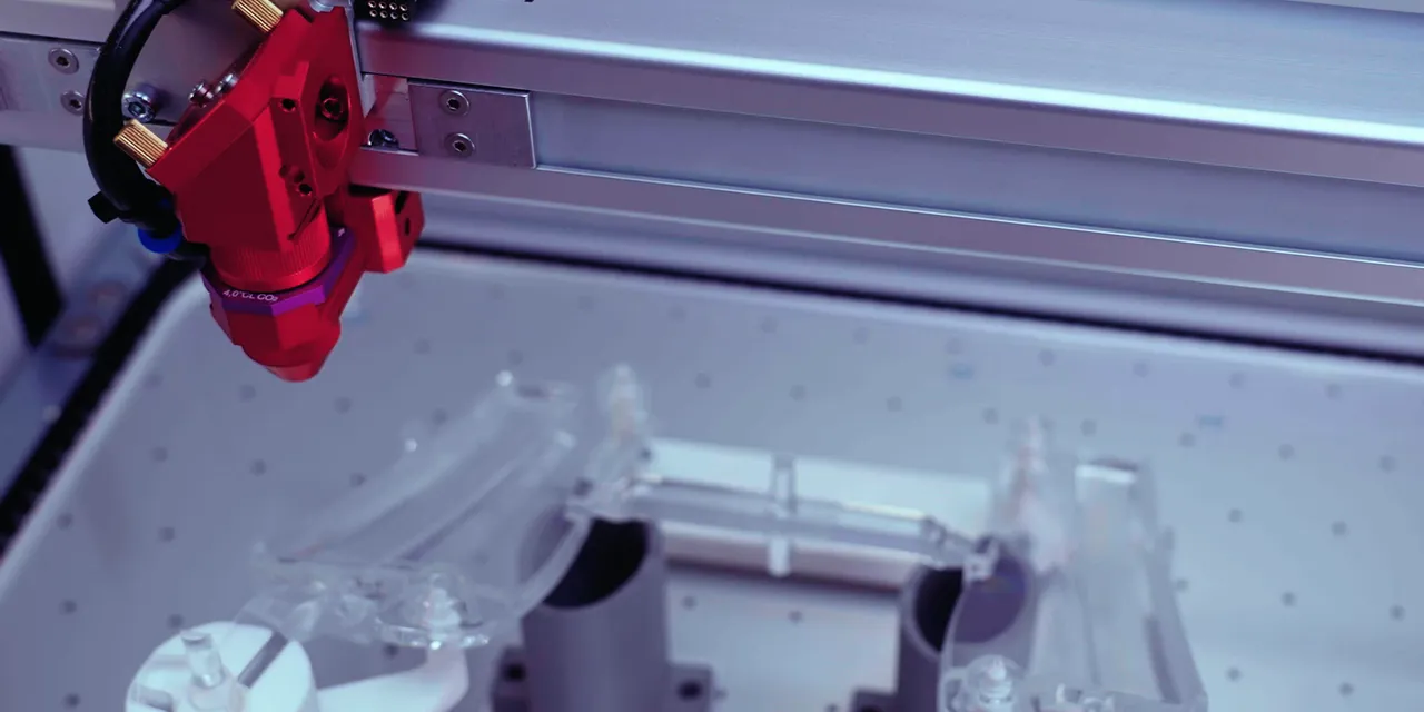Trotec Speedy serisi CO₂ lazer kesici, çalışma masası üzerinde hassas lens kafası ve özel jig ile
