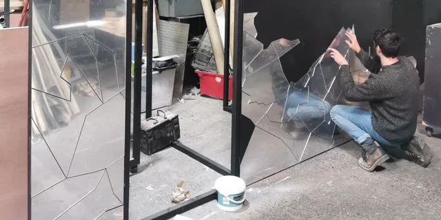 Technician applying laser-cut acrylic panels to wall for decorative installation