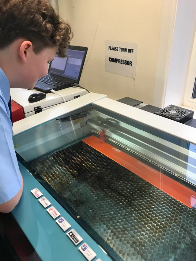 Student observing Trotec laser cutter engraving material inside Speedy series CO₂ laser machine