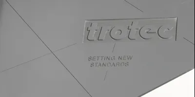 Trotec laser-engraved acrylic sign with logo and 'Setting New Standards' slogan