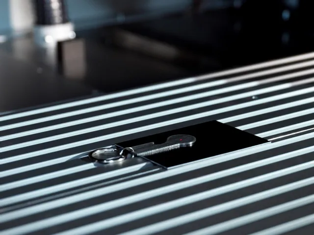 Porte-clés de marquage laser SpeedMarker de Trotec sur plaque métallique avec point laser rouge de précision