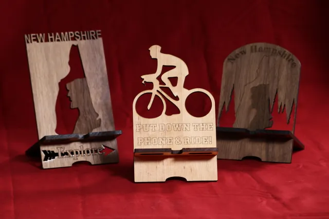 Custom wood phone stands laser cut with Trotec CO₂ laser featuring New Hampshire and cycling themes