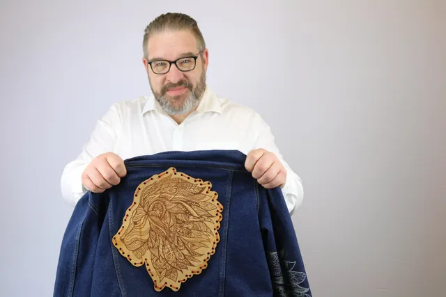 Man showing denim jacket with intricate lion head engraving made using Trotec laser cutter