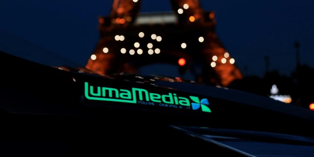 LumaMedia illuminated sign with Eiffel Tower blurred in the background at night