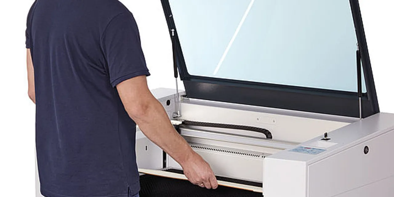 Operator placing material into Trotec Speedy series CO₂ laser cutter for engraving