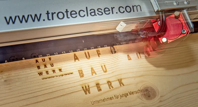 Trotec CO₂ laser engraver etching text onto wooden surface with high precision