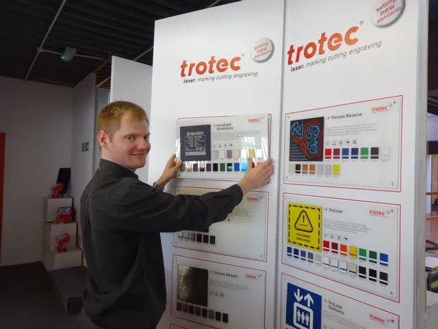 Ein Mann präsentiert mit Lasergravuren versehene Materialmuster von Trotec, darunter TroLase und eloxiertes Aluminium