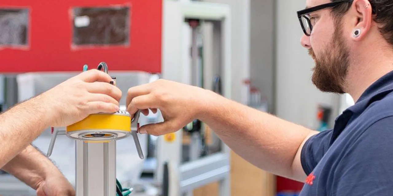 Technicy Trotec montują komponent do maszyny do grawerowania laserowego w zakładzie produkcyjnym.