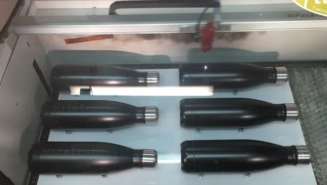 Trotec laser engraving black stainless bottles using Speedy series CO₂ laser cutter