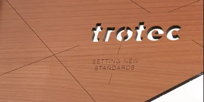 Le panneau en bois découpé et gravé au laser de Trotec met en valeur la précision avec un slogan qui établit de nouvelles références