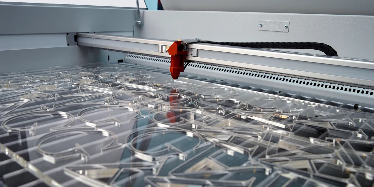 Laser cutter Trotec che incide lettere in acrilico trasparente con precisione