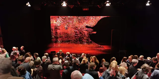 Audience gathering in front of a red laser-cut stage set possibly made using Trotec laser technology