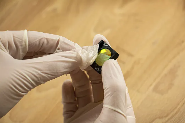 Manos con guantes sujetando la lente láser de CO₂ para el mantenimiento de la máquina de grabado láser Trotec