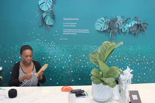 Woman crafting engraved wood piece in creative space featuring Trotec laser-cut wall design