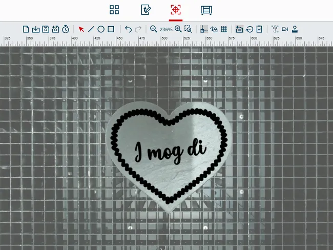 Metal heart engraved with 'I mog di' using Trotec laser cutter on honeycomb cutting table