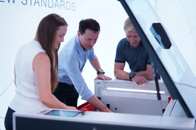 Team examining Trotec laser cutter with Ruby software interface during product demo