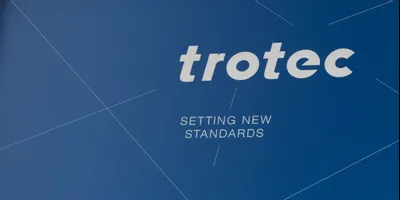 Trotec-Logo und Slogan 'Setting new standards' auf blauem Hintergrund