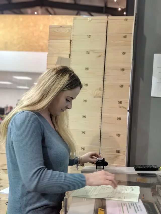 Woman preparing files for laser engraving near stacked wooden boxes in Trotec workspace