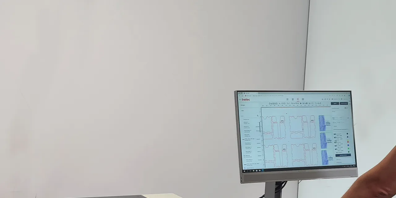 User operating Trotec laser cutter with Ruby software interface on monitor