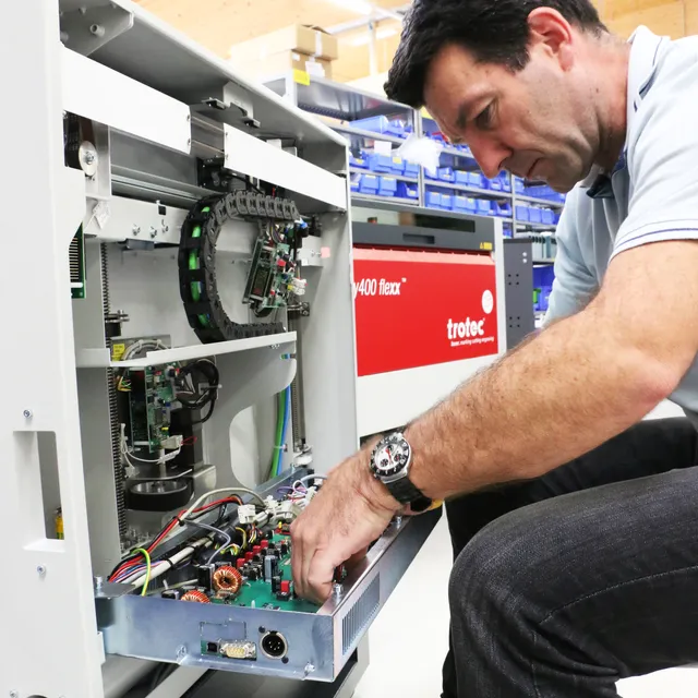 Technicien chargé de l'entretien des composants internes d'une machine à gravure laser Speedy 400 flexx de Trotec.