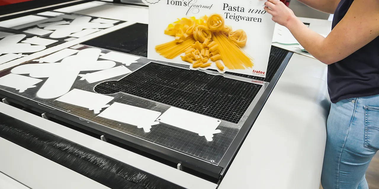 Trotec laser cutter processing signage display with pasta design and custom cut shapes