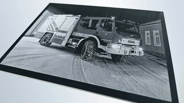 Imagen detallada de un camión de bomberos grabada en metal negro con la máquina de grabado láser Trotec