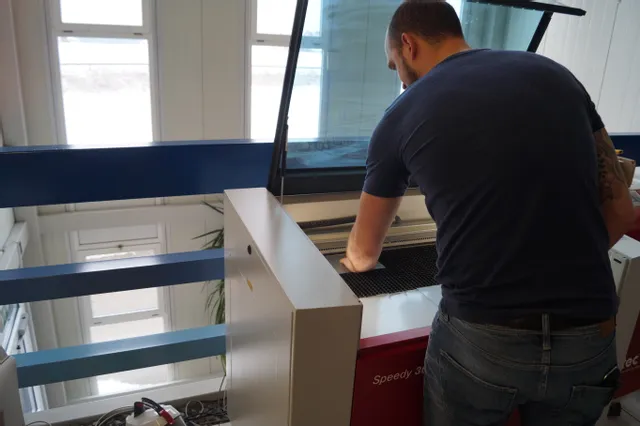 Operator setting material inside Trotec Speedy 360 CO₂ laser cutter for engraving