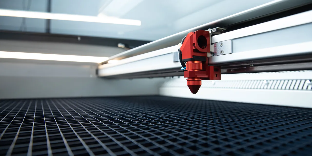 Close-up of Trotec Speedy series CO₂ laser cutter head over engraving bed