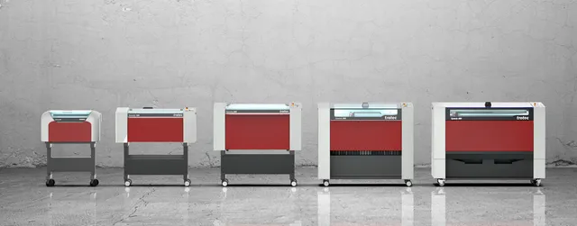 Aufstellung der CO₂ Lasergraviermaschinen der Trotec Speedy-Serie in verschiedenen Größen vor einer Betonwand