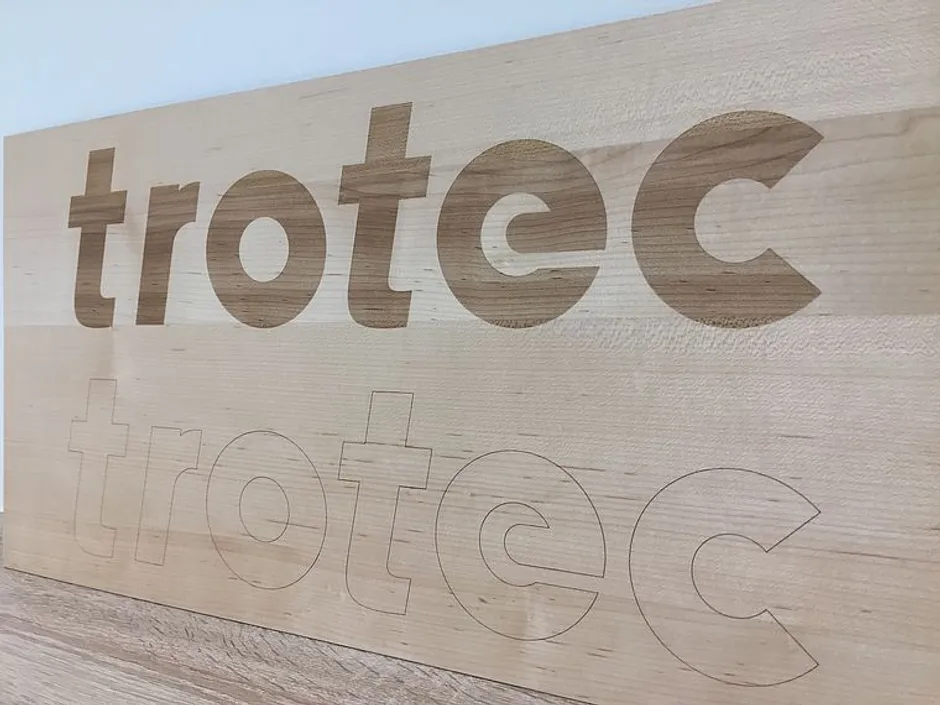 Trotec laser engraved and outlined logo on wooden surface using CO₂ laser cutter