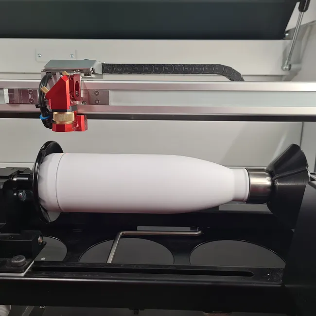 Trotec laser cutter engraving white tumbler using rotary attachment