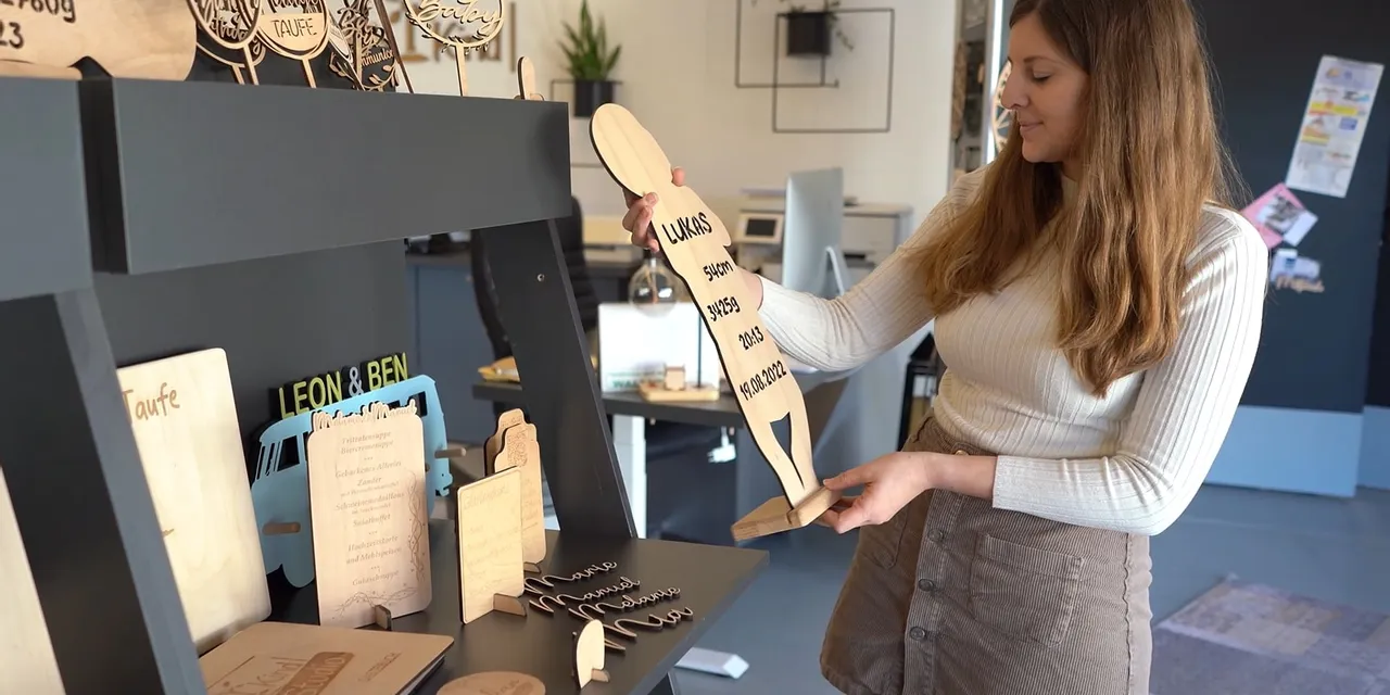 Woman displaying wooden signs created with Trotec CO₂ laser engraving machine