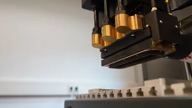 Tête de la machine de marquage laser SpeedMarker de Trotec positionnée au-dessus de la zone de travail en métal