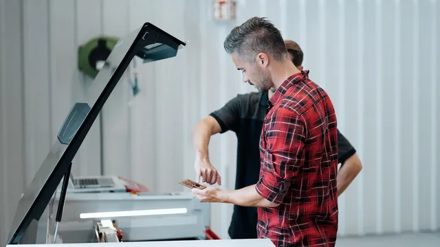 Two men inspecting engraved material from a Trotec Speedy series laser cutter