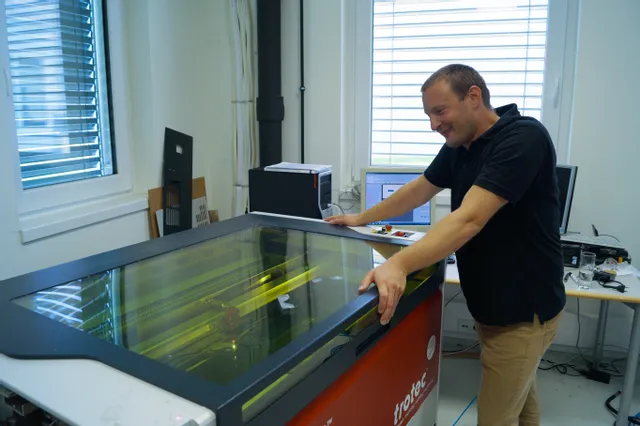 Ein Mann bedient einen Laserschneider der Speedy-Serie von Trotec in einem modernen Arbeitsraum.