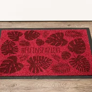 Laser-engraved doormat with tropical leaf pattern and HEREINSPAZIERT text made using Trotec laser cutter